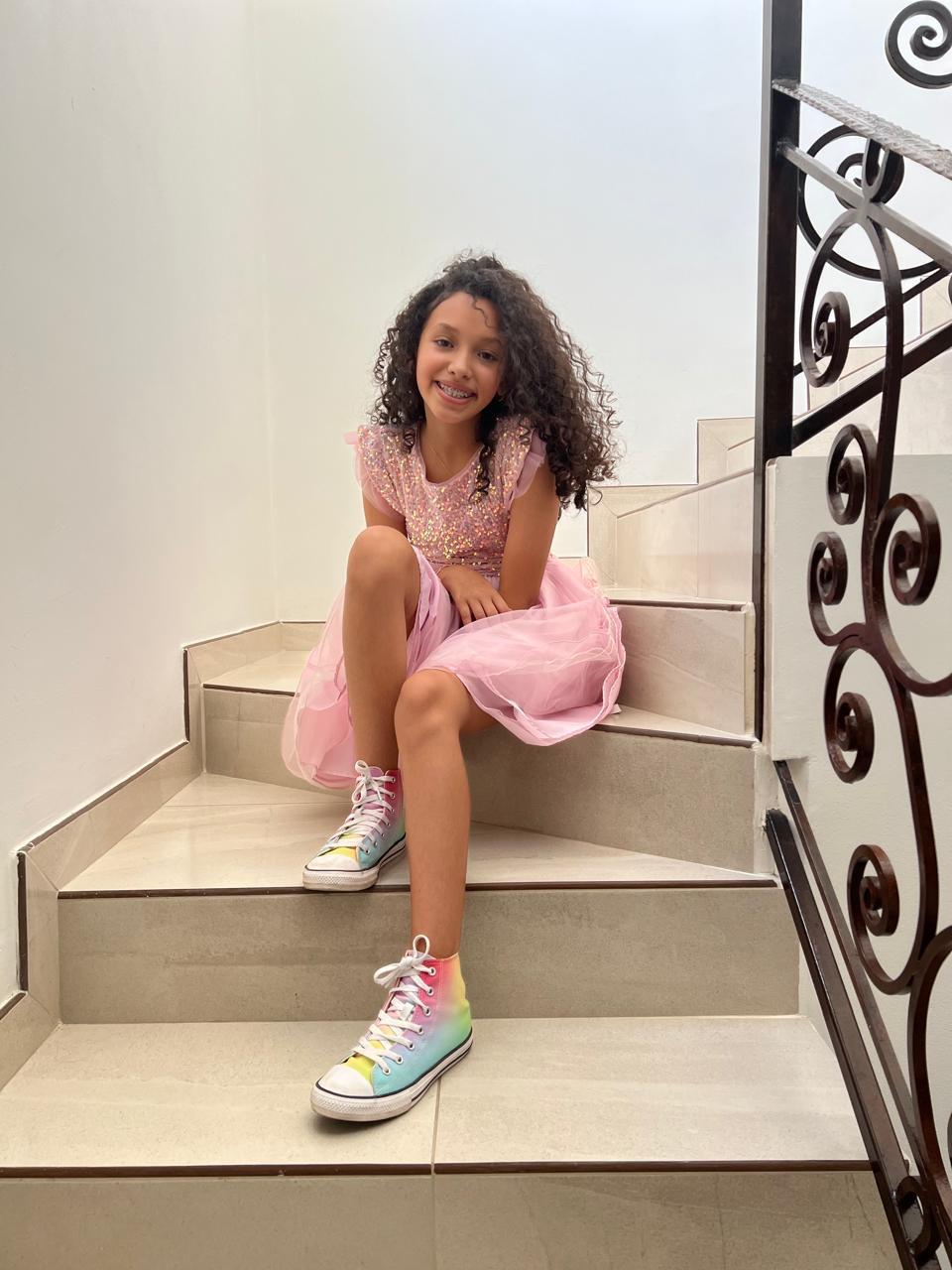 Fernanda sentada en las escaleras con vestido rosa